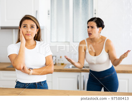 Woman ignoring her girlfriend standing in background and arguing with her Woman ignoring her girlfriend standing in background and arguing with her 97580413