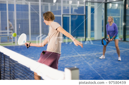 Guy playing paddle tennis on padel court indoors Guy playing paddle tennis on padel court indoors 97580439
