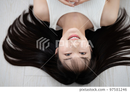 Young woman in tank top lying on flooring Young woman in tank top lying on flooring 97581246