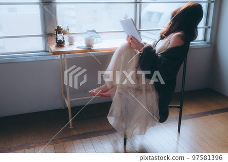 Photo of a young woman reading in her room Photo of a young woman reading in her room 97581396