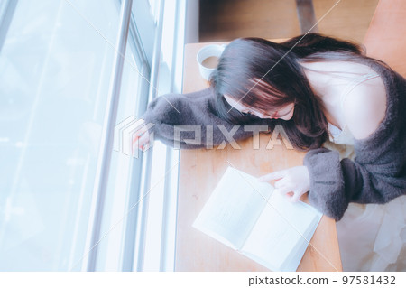 Photo of a young woman reading in her room Photo of a young woman reading in her room 97581432