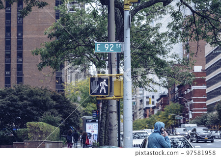 East 92 street sign in Manhattan, can walk signal, and a man holding his phone East 92 street sign in Manhattan, can walk signal, and a man holding his phone 97581958