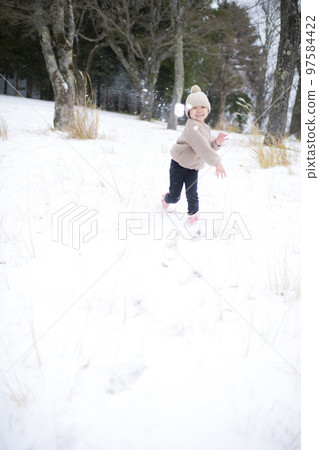 Girl throwing a snowball in a snowball fight 97584422