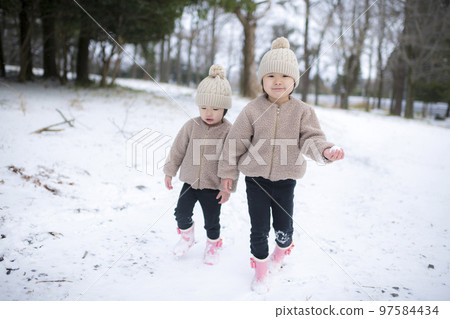 冬天戴著針織帽在雪地裡玩耍的女孩姐妹 97584434