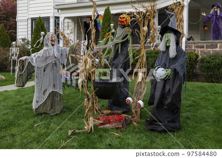 Many colorful Halloween decorations, skeletons, scarecrows at driveway and front lawn of house. Many colorful Halloween decorations, skeletons, scarecrows at driveway and front lawn of house. 97584480