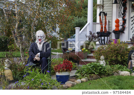 Many colorful Halloween decorations, skeletons, scarecrows at driveway and front lawn of house. Many colorful Halloween decorations, skeletons, scarecrows at driveway and front lawn of house. 97584484