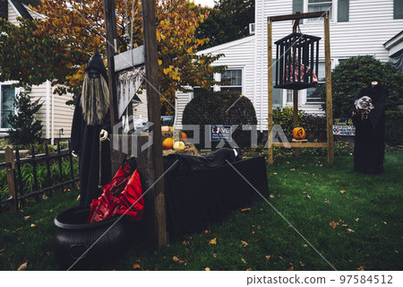 Many colorful Halloween decorations, skeletons, scarecrows at driveway and front lawn of house. 97584512