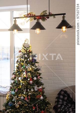 The black lampshade in the industrial loft style is decorated with spruce branches for Christmas and New Year on the background white brick wall. Close-up, minimalism 97587334