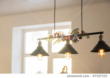 The black lampshade in the industrial loft style is decorated with spruce branches for Christmas and New Year on the background white brick wall. Close-up, minimalism 97587335