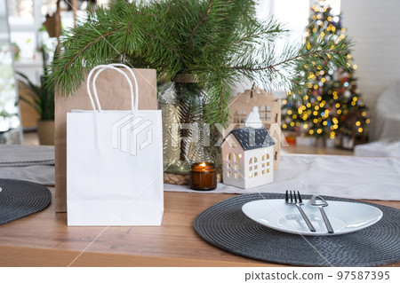Paper packages mock up are on kitchen served table decorated for Christmas. Shopping and gifts, present and ready meals are delivered and prepared for the new year Paper packages mock up are on kitchen served table decorated for Christmas. Shopping and gifts, present and ready meals are delivered and prepared for the new year 97587395