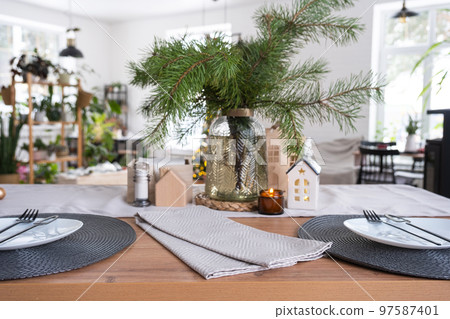 Festive Christmas decor in white kitchen, festive breakfast, white scandi interior. The figure of a cozy house ion the set table. New Year, mood, cozy home. Copy space 97587401