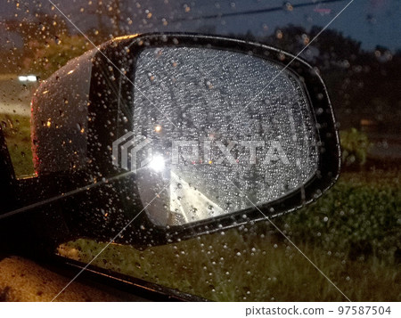 View from inside car through window to see wing mirror while of blur background at night time View from inside car through window to see wing mirror while of blur background at night time 97587504