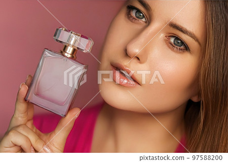 Perfume, beauty product and cosmetics model face portrait on pink background, beautiful woman holding fragrance bottle with floral feminine scent, fashion and makeup concept 97588200