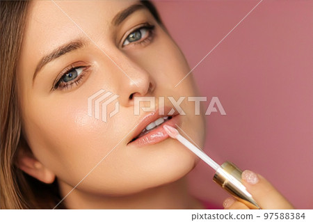 Beauty, makeup and skincare cosmetics model face portrait on pink background, beautiful woman applying lip gloss, perfect healthy skin glow, facial care closeup Beauty, makeup and skincare cosmetics model face portrait on pink background, beautiful woman applying lip gloss, perfect healthy skin glow, facial care closeup 97588384