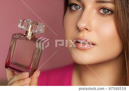 Perfume, beauty product and cosmetics model face portrait on pink background, beautiful woman holding fragrance bottle with floral feminine scent, fashion and makeup concept Perfume, beauty product and cosmetics model face portrait on pink background, beautiful woman holding fragrance bottle with floral feminine scent, fashion and makeup concept 97588519