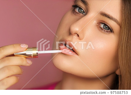 Beauty, makeup and skincare cosmetics model face portrait on pink background, beautiful woman applying lip gloss, perfect healthy skin glow, facial care closeup 97588753