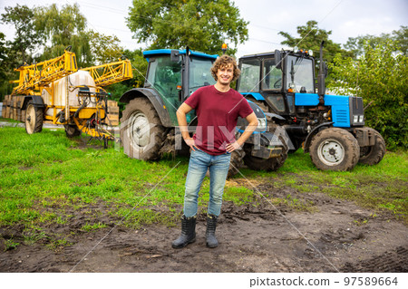 Joyous farmer standing in front of the tractor 97589664