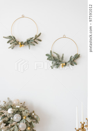 Stylish Christmas wreaths on white wall in home interior 97591012