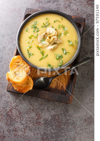 Vegetarian artichoke soup served with toasted bread close-up in a bowl. Vertical top view 97591140