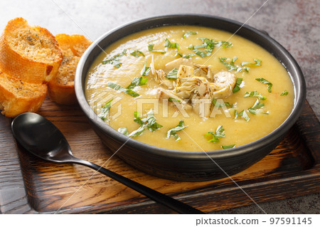 Vegetable cream soup of artichokes, potatoes, leeks and garlic served with toasted bread close-up in a bowl. Horizontal 97591145