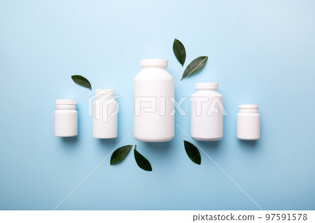 supplement pills with medicine bottle health care and medical top view. Vitamin tablets. Top view mockup bottle for pills and vitamins with green leaves, natural organic bio supplement, copy space 97591578