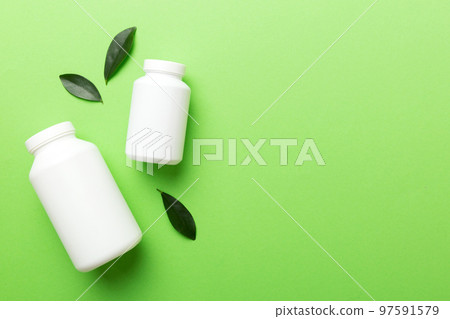 supplement pills with medicine bottle health care and medical top view. Vitamin tablets. Top view mockup bottle for pills and vitamins with green leaves, natural organic bio supplement, copy space 97591579