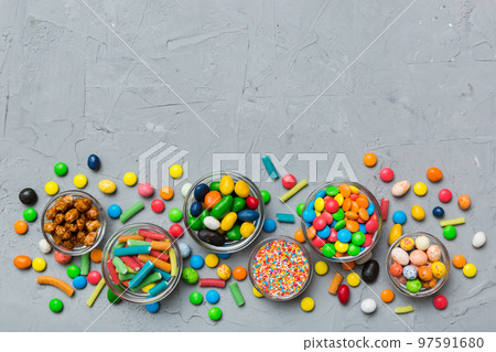 different colored round candy in bowl and jars. Top view of large variety sweets and candies with copy space different colored round candy in bowl and jars. Top view of large variety sweets and candies with copy space 97591680