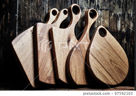 Different kind of wooden cuttng board placed vertically on wooden background Different kind of wooden cuttng board placed vertically on wooden background 97592103