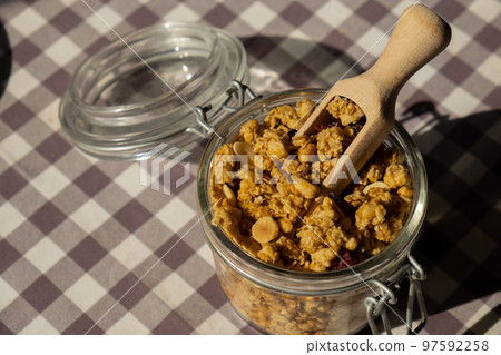 Homemade granola with nuts and seeds in eco glass jar. Healthy snack on breakfast. Muesli from oatmeal, raisins, honey, cranberry, flax, almond, cashew, freshly baked Homemade granola with nuts and seeds in eco glass jar. Healthy snack on breakfast. Muesli from oatmeal, raisins, honey, cranberry, flax, almond, cashew, freshly baked 97592258