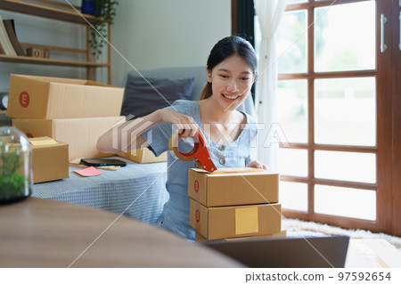 Starting small business entrepreneur of independent Asian female online seller packing products to send to customers and SME delivery concept. 97592654