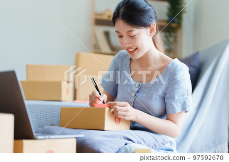 Starting small business entrepreneur of independent young Asian woman online seller is using computer and taking orders to pack products for delivery to customers. SME delivery concept. 97592670