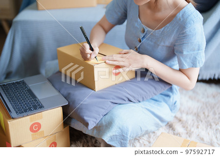 Starting small business entrepreneur of independent young Asian woman online seller is using computer and taking orders to pack products for delivery to customers. SME delivery concept. Starting small business entrepreneur of independent young Asian woman online seller is using computer and taking orders to pack products for delivery to customers. SME delivery concept. 97592717