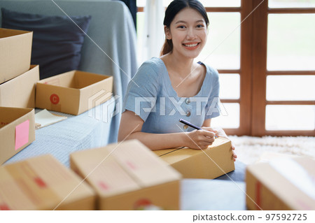 Starting small business entrepreneur of independent young Asian woman online seller is using computer and taking orders to pack products for delivery to customers. SME delivery concept. Starting small business entrepreneur of independent young Asian woman online seller is using computer and taking orders to pack products for delivery to customers. SME delivery concept. 97592725