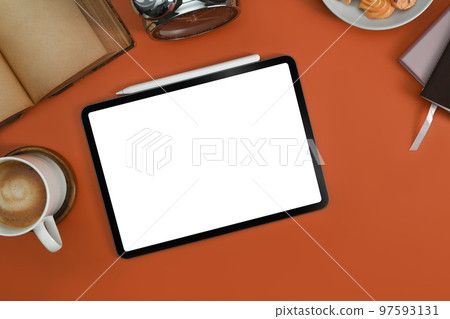 Flat lay digital tablet with white screen, coffee cup and book on orange background 97593131