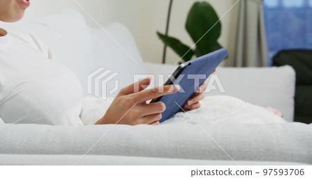 Woman hold with tablet computer and sit on sofa at home Woman hold with tablet computer and sit on sofa at home 97593706