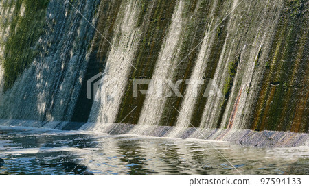 River dam with clear flowing water on a warm day 97594133