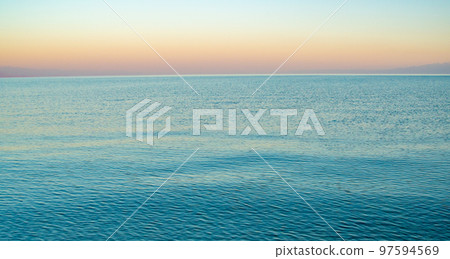 The surface of the water in the Issyk Kul mountain lake in Kyrgyzstan at sunset.Pastel and soft tones of water and sky against the background of mountains. The surface of the water in the Issyk Kul mountain lake in Kyrgyzstan at sunset.Pastel and soft tones of water and sky against the background of mountains. 97594569