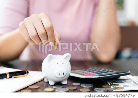 Closeup of woman hand putting money coin into piggy bank for saving money. saving money and financial concept Closeup of woman hand putting money coin into piggy bank for saving money. saving money and financial concept 97594779