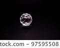 Faceted sphere, sparkling crystal on dark, black background. Large glass with light refraction, stone backdrop. Empty space for inscriptions 97595508
