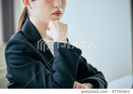 一個年輕女人把下巴擱在桌子上思考 97595663