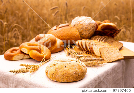 lot of different flavored bread, wheat, rye, on the table in the field outside lot of different flavored bread, wheat, rye, on the table in the field outside 97597460