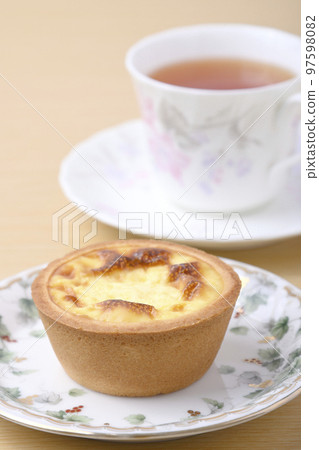 Tea time with Portuguese egg tarts and black tea on a wooden table. Tea time with Portuguese egg tarts and black tea on a wooden table. 97598082