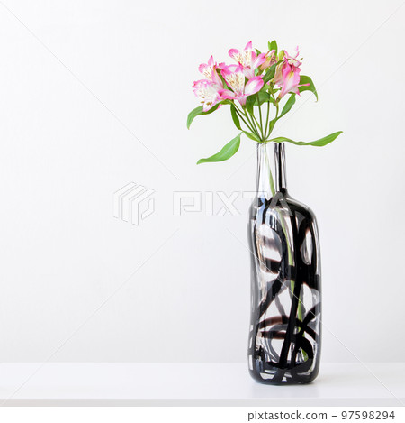 Pink alstroemeria in glass vase on white table Pink alstroemeria in glass vase on white table 97598294