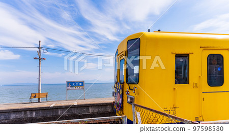 A yellow train with a beautiful sea in the background "Daisami-Higashi Station" A tourist attraction famous for yellow handkerchiefs and commercial filming locations: Shimabara City, Nagasaki Prefecture 97598580