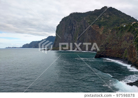 View of beautiful mountains and water on Madeira island, Portugal. Scenic and beautiful nature. Observation deck. Green mountains on the island. View of the Atlantic Ocean. View of beautiful mountains and water on Madeira island, Portugal. Scenic and beautiful nature. Observation deck. Green mountains on the island. View of the Atlantic Ocean. 97598878