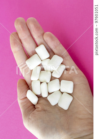 Lots of chewing gum in a woman's hand on a bright pink background 97601051