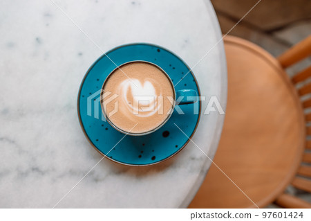 Turquoise mug of flat white coffee with heart shaped latte art on white table at the hipster coffee shop. Flat lay, copy space Turquoise mug of flat white coffee with heart shaped latte art on white table at the hipster coffee shop. Flat lay, copy space 97601424