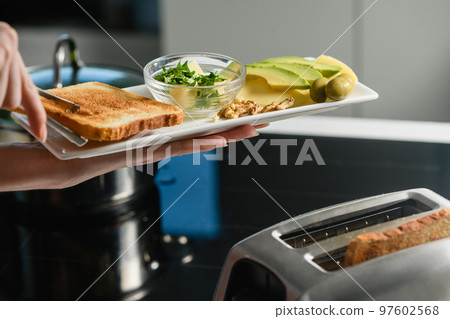 Woman's hand puts freshly baked toast on a plate 97602568