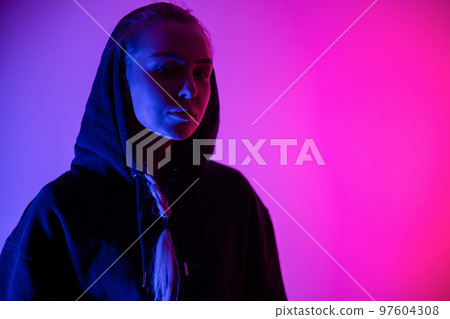 Colorful low-key portrait of a cool and confident blonde woman in hoodie Colorful low-key portrait of a cool and confident blonde woman in hoodie 97604308