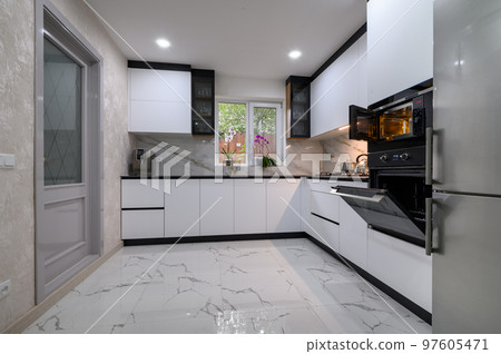 A sleek, modern kitchen with white cabinets, a marble floor 97605471